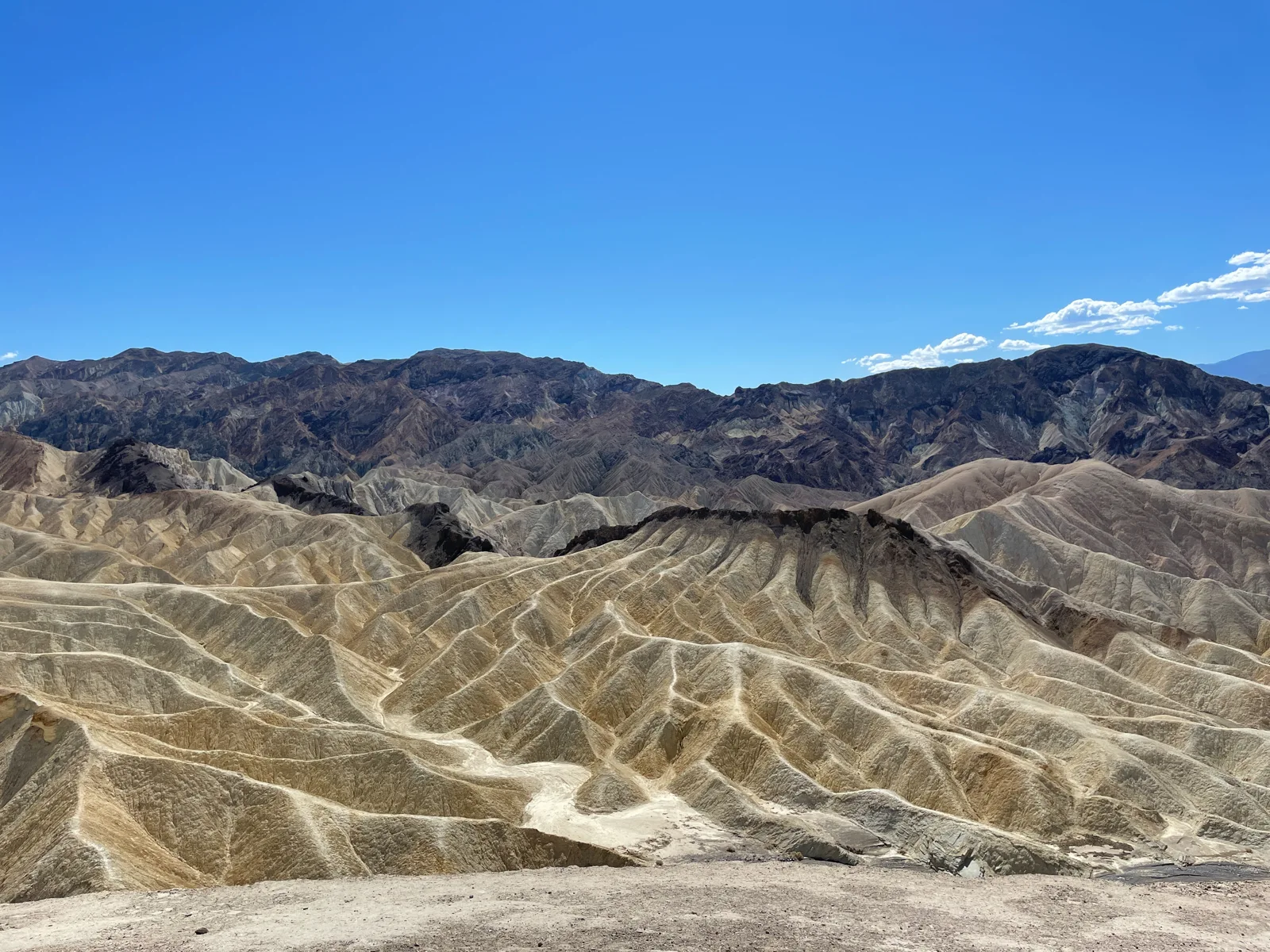 Sunlit ridges at Zabriskie Point in Death Valley beneath a clear blue sky.